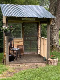 a small wooden shed sitting next to a tree with a chair on top of it