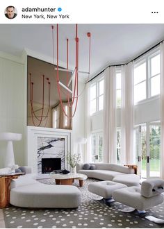 a living room filled with white furniture and lots of windows next to a fire place