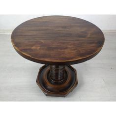 a round wooden table sitting on top of a white floor