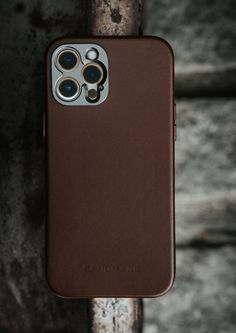 an iphone case sitting on top of a wooden pole with two binoculars in the back