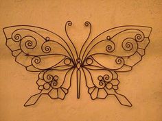 a metal butterfly with swirls on it's wings is mounted to the wall