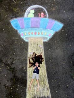 a woman standing in front of a chalk drawing of an alien ship on the ground