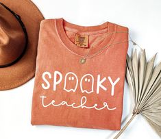 a t - shirt that says spooky teacher next to a hat