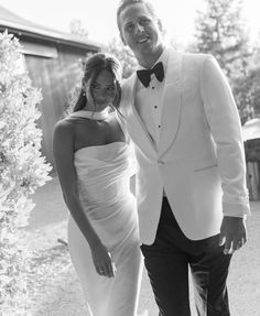 a man in a tuxedo standing next to a woman in a white dress