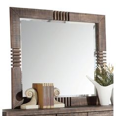 a mirror sitting on top of a wooden dresser next to a vase with flowers in it