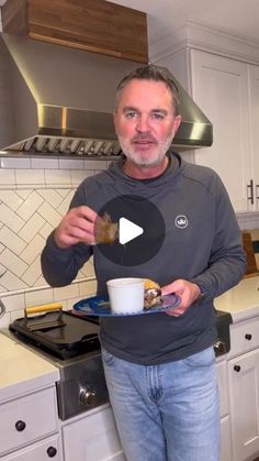 a man standing in a kitchen holding a plate with food on it