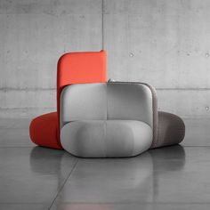 an orange and grey couch sitting on top of a floor next to a white wall