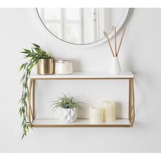 two shelves with candles and plants on them in front of a round mirror above it