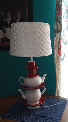 a lamp that is sitting on top of a table next to a tea pot and saucer