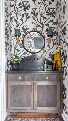 a bathroom vanity with a mirror above it and wallpaper on the walls behind it