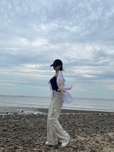 a woman is walking on the beach near the water