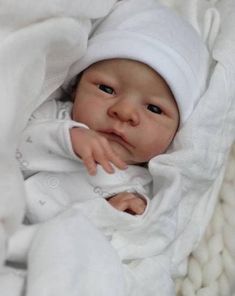 a newborn baby wrapped in a blanket looking at the camera