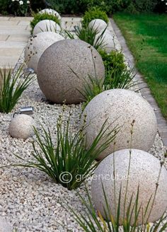 some very pretty rocks and plants by the sidewalk