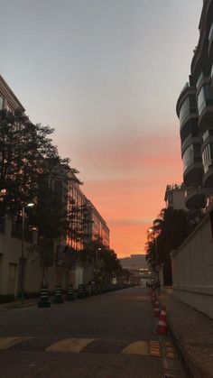 the sun is setting on an empty street in front of some buildings with balconies