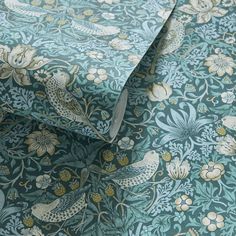 a blue and gold wallpaper with white birds on green leaves, flowers and vines