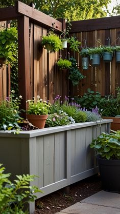 an outdoor garden area with potted plants and hanging planters on the fence line