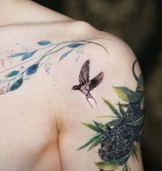 a close up of a person's shoulder with a bird on it and flowers