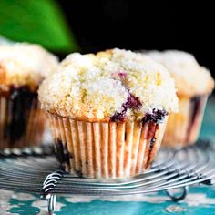 three blueberry muffins sitting on top of a cooling rack with one muffin missing