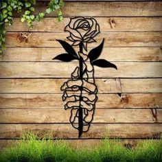 a wooden wall with a metal rose on it and vines growing out of the side