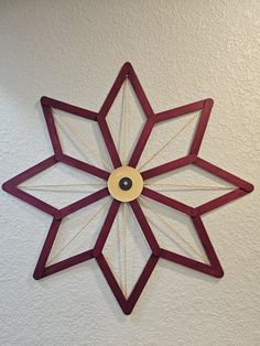 a clock made out of wood and string with a wooden star on the wall behind it