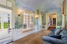 a living room filled with furniture next to a window covered in wallpaper and paintings