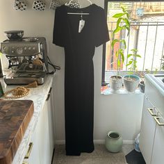 a black dress is hanging on the wall next to a potted plant in a kitchen