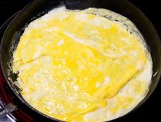 an omelet is being cooked in a skillet on the stove with tongs