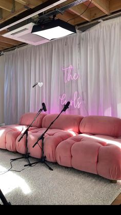 two microphones sitting on top of a pink couch in front of a white curtain