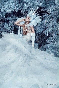 a woman sitting in a chair with white feathers on her head and wings around her body