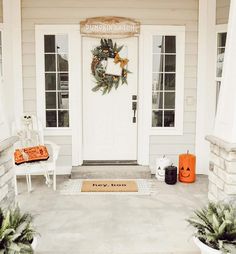 a front porch decorated for halloween with pumpkins and wreath