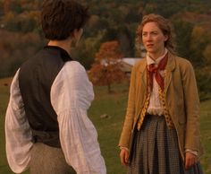 two people standing in a field talking to each other