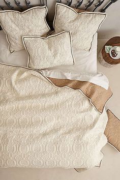 a bed with white sheets and pillows on top of it