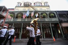 the band is marching down the street in front of an old building with flags on it