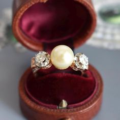 Antique trilogy ring circa 1890 crafted in 18-karat gold, adorned with a pearl and two old-cut diamonds. The pearl, likely natural, has a diameter of 9mm and displays a beautiful luster. The ring is enhanced with two old-cut diamonds, each weighing approximately 0.15 carats, with an estimated color and clarity of G-H and SI/I respectively. The band is elegantly engraved. Weight: 5g Size: 56 FR (7.75 US - P 1/2 UK) Metal: 18-karat Gold Stones: Diamonds (0.15 ct each, G-H color, SI/I clarity) and Natural Pearl Ring, Pearl And Diamond Ring, Antique Diamond Rings, Jewelry By Material, Pave Pendant, Antique Ring, Luxury Rings, 18k Gold Ring, Sapphire Earrings