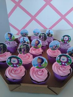 cupcakes with pink frosting and dora the explorer images on them in a cardboard box