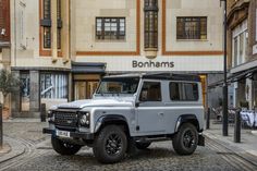 a silver land rover is parked in front of a building on a cobblestone street