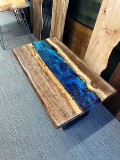 a wooden bench sitting on top of a carpeted floor next to a blue table