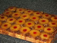 pineapple upside down cake sitting on top of a granite countertop with red cherries