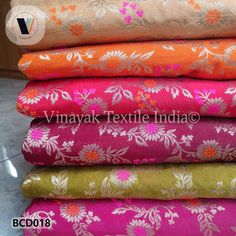 several different colored fabrics stacked on top of each other in various sizes and colors, all with