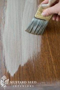 someone using a brush to paint a wood table with white and brown stain on it