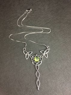 "I will fabricate this Celtic inspired pendant necklace, in sterling silver, featuring a center, faceted 8mm faceted Peridot! The frame, or centering, of the pendant is made with Celtic Trinity Knots and sterling wire work braids down the center to add the balancing touches to the piece. It comes with a sterling box chain which is soldered to each end of the pendant. This piece is 18\" in length, including the chain, and the pendant, itself, is approximately 2 1/2 inches in height and approximat Silver Faceted Sterling Silver Birthstone Necklace, Silver Pendant Crystal Necklace For May Birthstone, Sterling Silver Faceted Pendant Birthstone Necklace, May Birthstone Jewelry In Silver With Peridot, Silver Peridot Jewelry For May Birthstone, Nickel-free Silver Peridot Jewelry, Faceted Sterling Silver Birthstone Necklace For Jewelry Making, Silver Faceted Peridot Jewelry, Handmade Silver Peridot Necklace