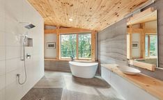 a bathroom with a tub, sink and large mirror in it's center wall