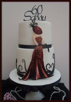 a white and black cake with a woman in a red dress on the top tier