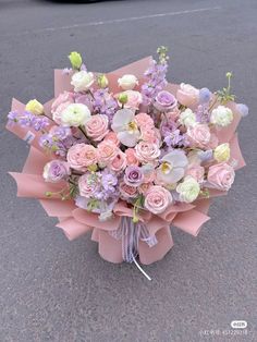 a bouquet of flowers sitting on the ground next to a parking lot in front of a car