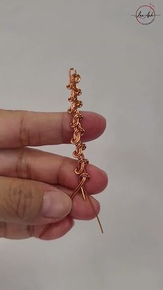 a person is holding up a tiny chain with two small hooks attached to the end