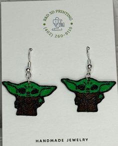 "Embrace the cuteness with our Grogu Earrings! These earrings are 3D printed, making them a unique addition to your jewelry collection. Perfect for any Star Wars fan, they'll add a touch of fun and whimsy to any outfit. May the fashion force be with you!" Themed Dangle Pierced Earrings, Themed Pierced Earrings As A Gift, Themed Earrings For Pierced Ears As Gift, Cute Green Earrings For Birthday, Themed Gift Earrings, Green Fun Earrings For Gift, Green Fun Earrings For Gifts, Fun Green Earrings For Gifts, Fun Green Earrings For Birthday