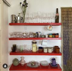 the shelves are filled with glasses, cups and vases on top of each shelf