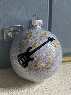 a christmas ornament with an electric guitar on it's side and music notes painted on the front