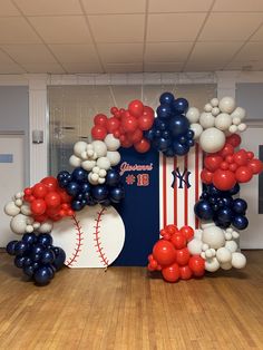 baseball themed balloon arch in the shape of an american flag and ball on a wooden floor