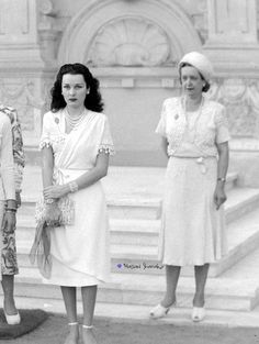 an old photo of three women standing in front of a building with statues behind them